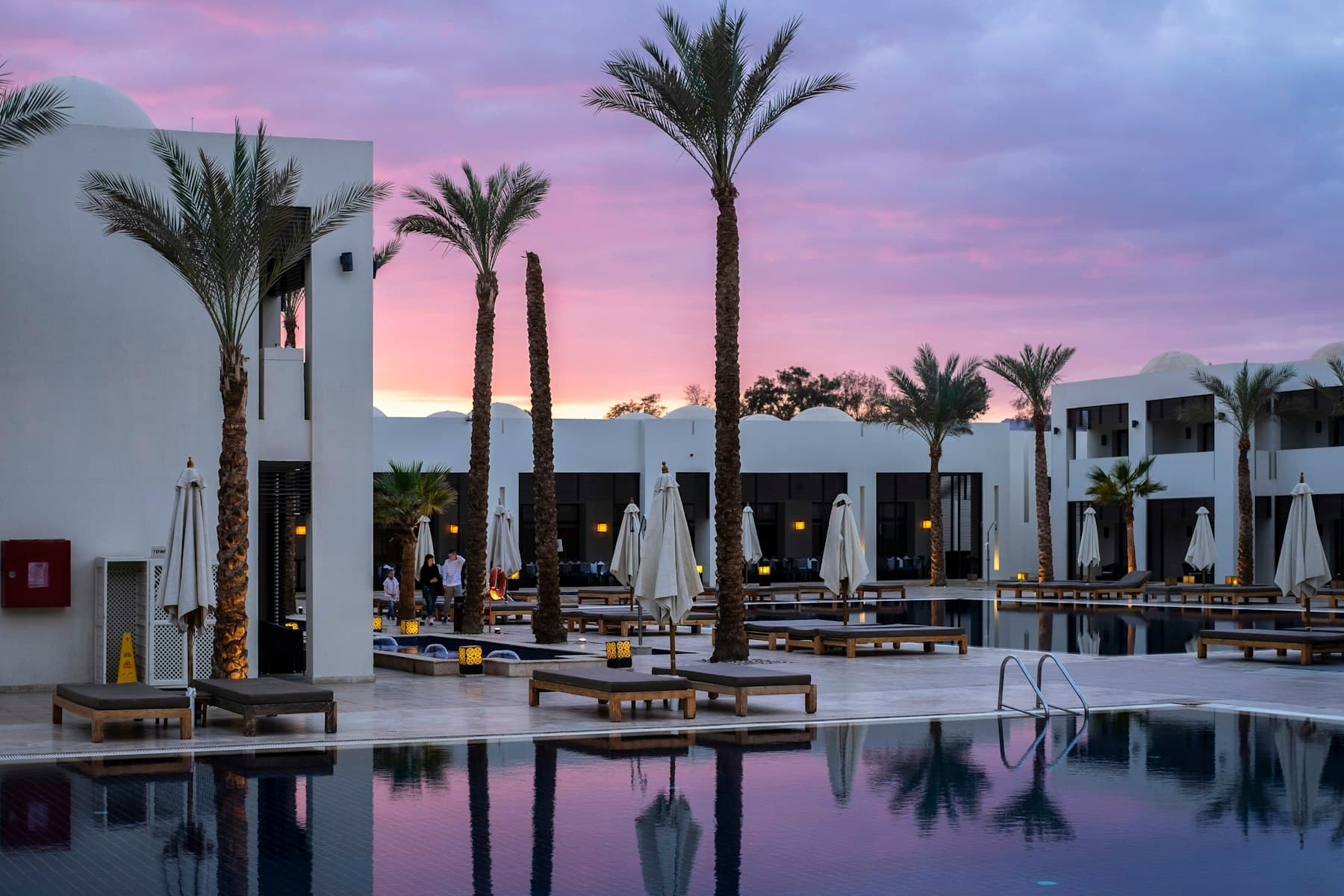 Palm-lined hotel pool at dusk