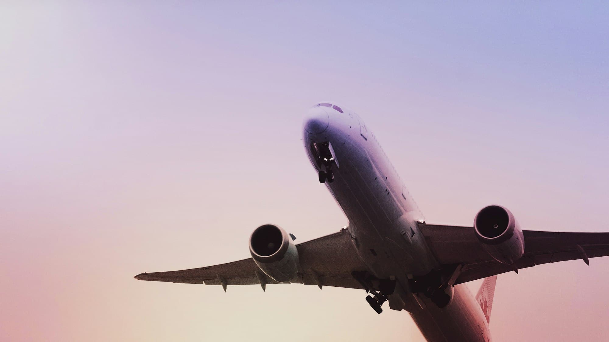 An aircraft climbing into a lilac evening sky